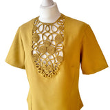 Mustard yellow vintage blouse with intricate cut-out rouleaux design on a mannequin against a white background