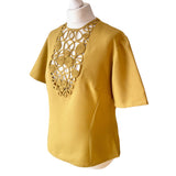 Mustard yellow vintage 1940s 1950s  blouse with intricate cut-out rouleaux design on a mannequin against a white background