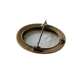 antique brass framed oval brooch on white background