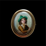 Antique brooch with a portrait of a  Hand Painted Victorian Tyrolean boy in a green hat on a black background.