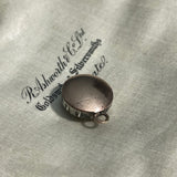 gold coloured back of a round antique Georgian pendant with one central large paste stone surrounded by 12 small ones on satin jewellery box background. Available via hurdyburdy vintage shop