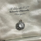 round antique Georgian pendant with one central large paste stone surrounded by 12 small ones on satin jewellery box background. Available via hurdyburdy vintage shop