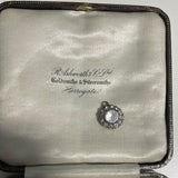 round antique Georgian pendant with one central large paste stone surrounded by 12 small ones on satin jewellery box background. Available via hurdyburdy vintage shop