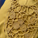 Close-up of a mustard yellow fabric with intricate hand stitched rouleaux design