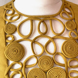 Decorative vintage blouse bib with interlocking circular rouleaux patterns on a white background